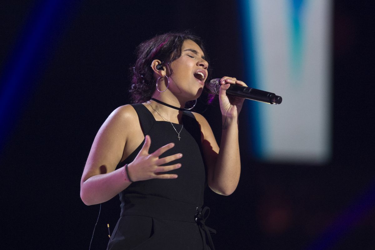 Female singer holds a microphone and sings with whole heart and eyes closed.